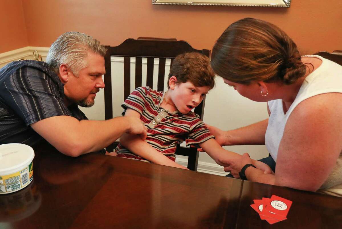 Brian and Piper Lindeen aid their son, Zach, as he experiences an epilepsy seizure Sunday, Dec. 2, 2018, in Sugar Land. The first FDA approved cannabis-based medication is available to U.S. patients through a prescription but its high cost, $32,500 a year, puts it out of reach of several patients. Some patients in Texas have opted to instead rely on the state's more affordable medical marijuana program, yet many patients remain locked out of the limited program.