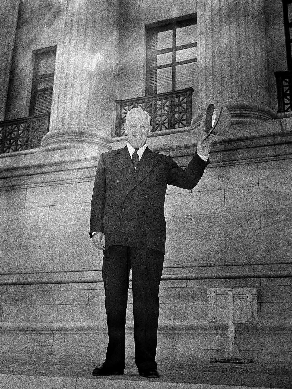 Earl Warren smiles and waves while standing at the base of the two pillars of the Supreme Court building in Washington, D.C., Oct. 5, 1953 after arriving to become the 14th Chief Justice of the United States. (AP Photo/Henry Griffin)