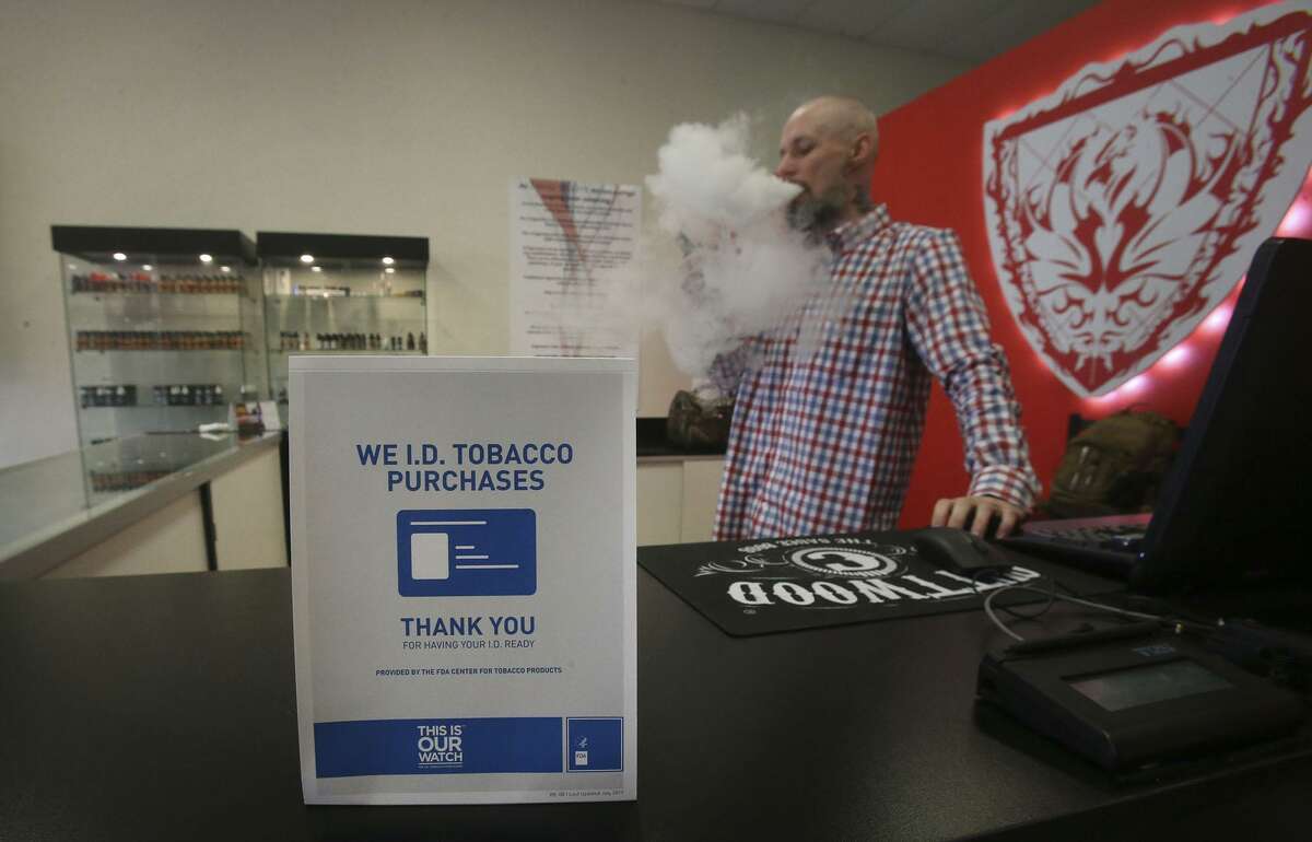 FILE - A sign on the counter at the Smoke to Live vape shop in San Antonio, Texas. Monday, the Texas Senate will hear state bill aimed to raise the purchasing age of all tobacco products, including cigarettes and e-cigarettes.