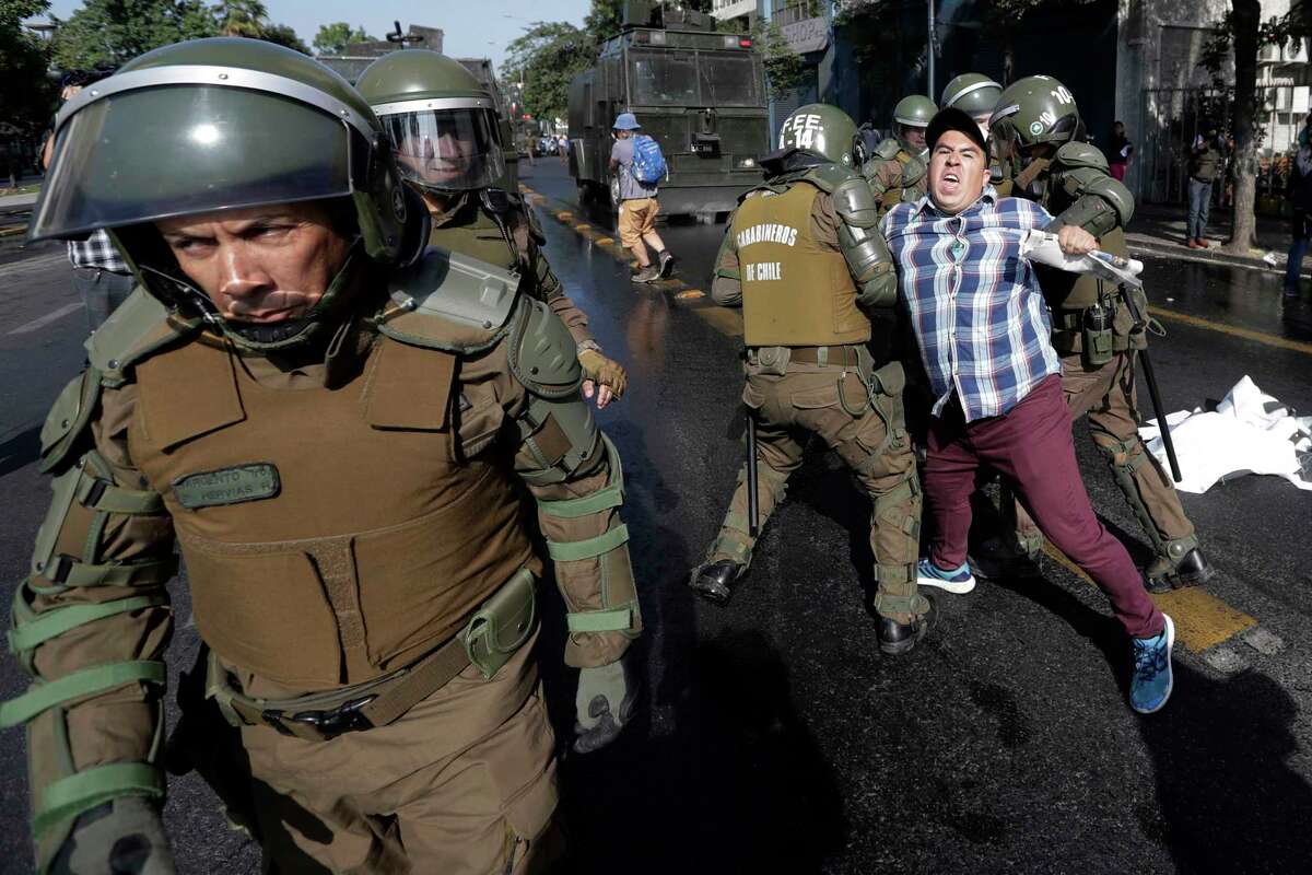 FILE - In this Jan. 16, 2018, file photo, a man is arrested during a protest against Pope Francis in Santiago, Chile. Francis' January visit was dominated by the clergy abuse scandal there, and featured unprecedented protests against a papal visit: churches were firebombed and riot police used water cannons to quell demonstrations. (AP Photo/Victor R. Caivano, File)