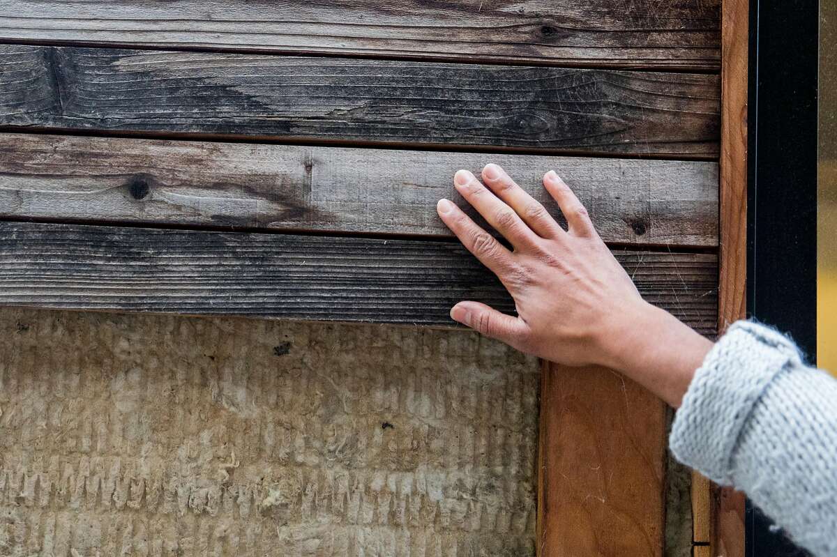 Siena Shaw runs her hands over the wooden paneling used to construct a sustainable tiny home, called the Mighty House, currently sitting in Menlo Park, Calif. Friday, Dec. 14, 2018.