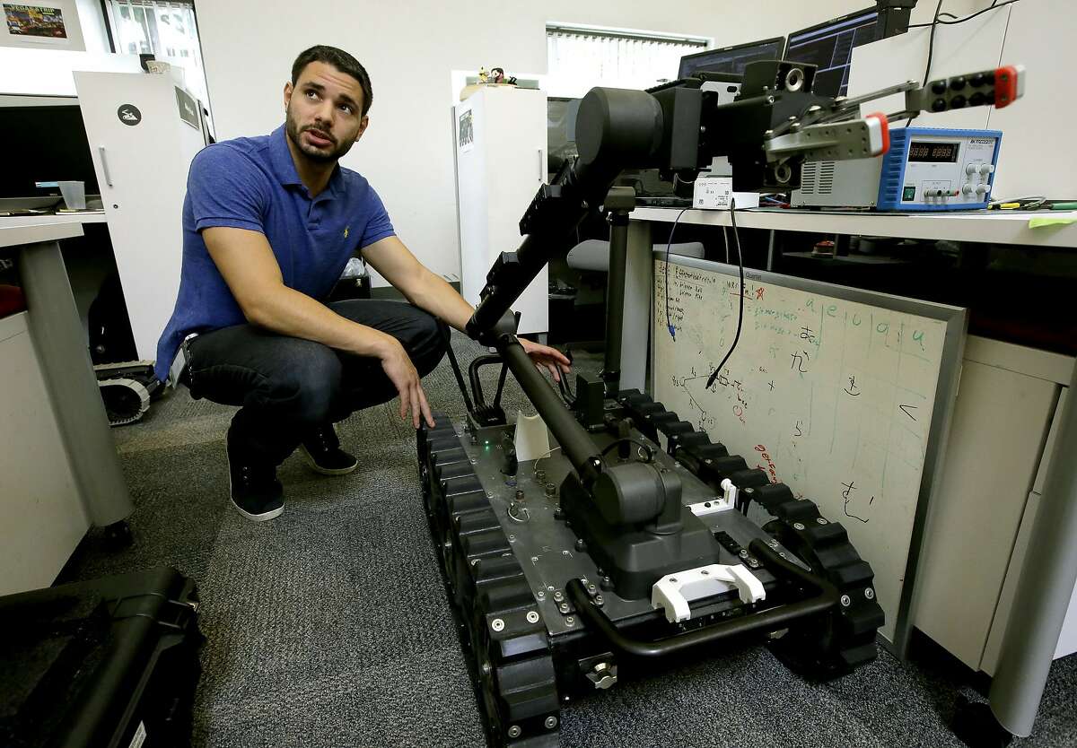 In this Aug. 28, 2018 photo, software engineer Nicholas Otero, of Woburn, Mass., speaks with a colleague about features on a Centaur robot, right, at Endeavor Robotics in Chelmsford, Mass. The Army is looking for a few good robots. These robots won’t fight, at least not yet. But they will be designed to help the men and women who do. The companies making them are waging a different kind of battle. At stake is a contract worth almost half a billion dollars for 3,000 backpack-sized robots that can defuse bombs and scout enemy positions. (AP Photo/Steven Senne)