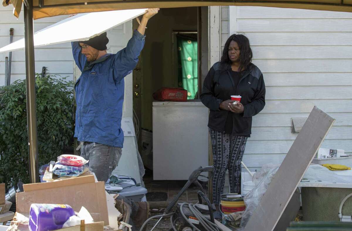 Ann Weston, right, stands in her backyard as Andrew Cobb, with West Street Recovery, moves sheetrock as the nonprofit works to fix the work done by the FEMA-funded Harvey home repair program known as PREPS Thursday, Dec. 20, 2018, in Houston.