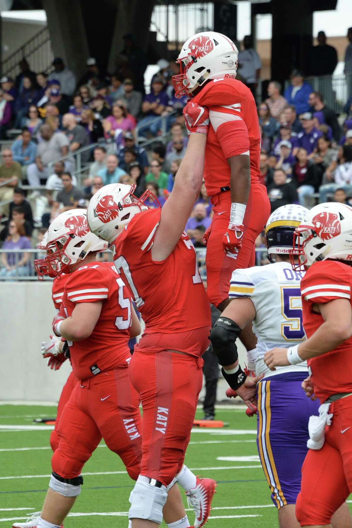 Cole Birmingham (77) of Katy hoists Deondrick Glass (2) in the air to celebrate his touchdown in the first quarter of a Class 6A Div. I Reg. III area-round playoff game between the Katy Tigers and the Jersey Village Falcons on Friday, November 23, 2018 at Legacy Stadium, Katy, TX.
