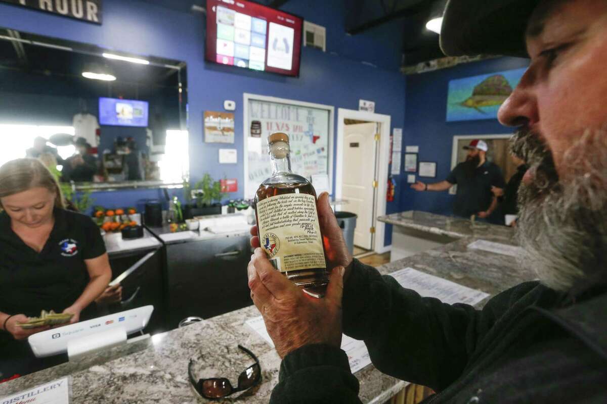 Scott Haley takes a look at a whiskey bottle at Texas Tail Distillery's Seawall Boulevard location on Saturday, Dec. 29, 2018, in Galveston. Texas Tail distills moonshine in a variety of flavors. It is an offshoot of Texas Tail vodka, which Greg Truex and partner Nick Droege started in Dallas in 2007.
