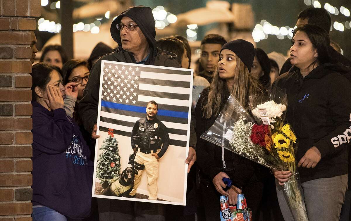 Family members of police Cpl. Ronil Singh including Birend Singh, holding picture at left, attend a candlelight vigil for the slain officer in downtown Newman, Calif. 