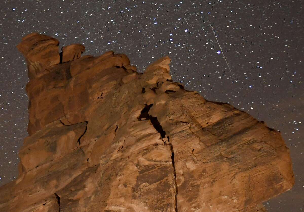 VALLEY OF FIRE STATE PARK, NEVADA - DECEMBER 14: A Geminid meteor streaks above one of the peaks of the Seven Sisters rock formation early on December 14, 2018 in the Valley of Fire State Park in Nevada. The meteor display, known as the Geminid meteor shower because it appears to radiate from the constellation Gemini, is thought to be the result of debris cast off from an asteroid-like object called 3200 Phaethon. The shower is visible every December. (Photo by Ethan Miller/Getty Images)