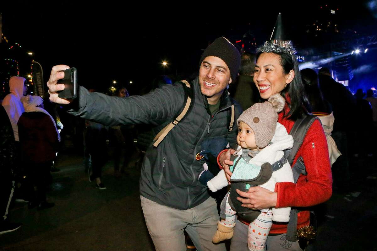 Michael Finelli takes a selfie with his wife, Rachael Nguyen and their nine-month-old daugther, Francine Nguyen-Finelli, while celebrating at the city's giant New Year's Eve party downtown at Hemisfair on Monday, Dec. 31, 2018.
