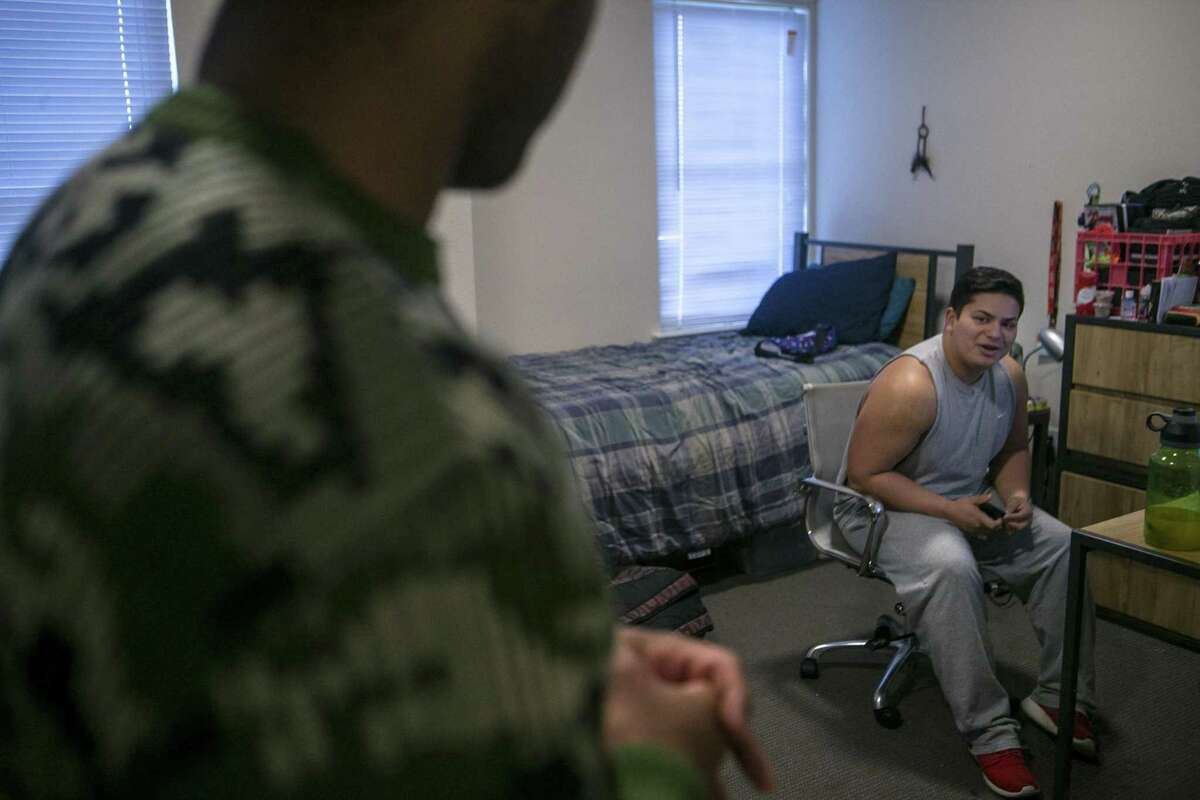 On the left, Israel Delarna, 19, talks his his roommate Miguel Alcorn, 22, in their dorm room.