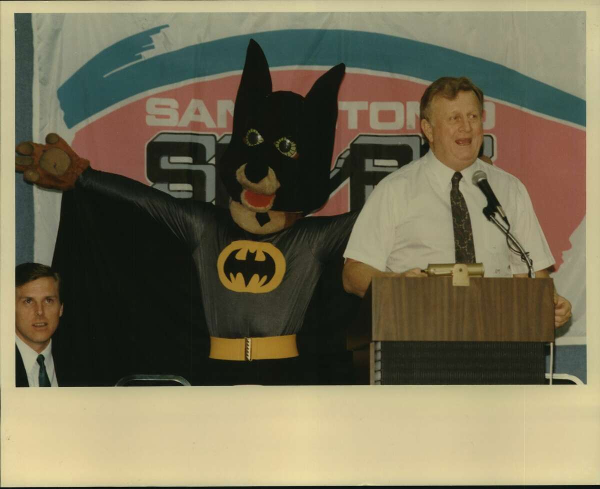 San Antonio Spurs draft, Arena; Red McCombs, owner, addresses crowd with thelp of Coyote mascot dressed as Batman; broadcaster Dave Barrett at left; NBA basketball 1989