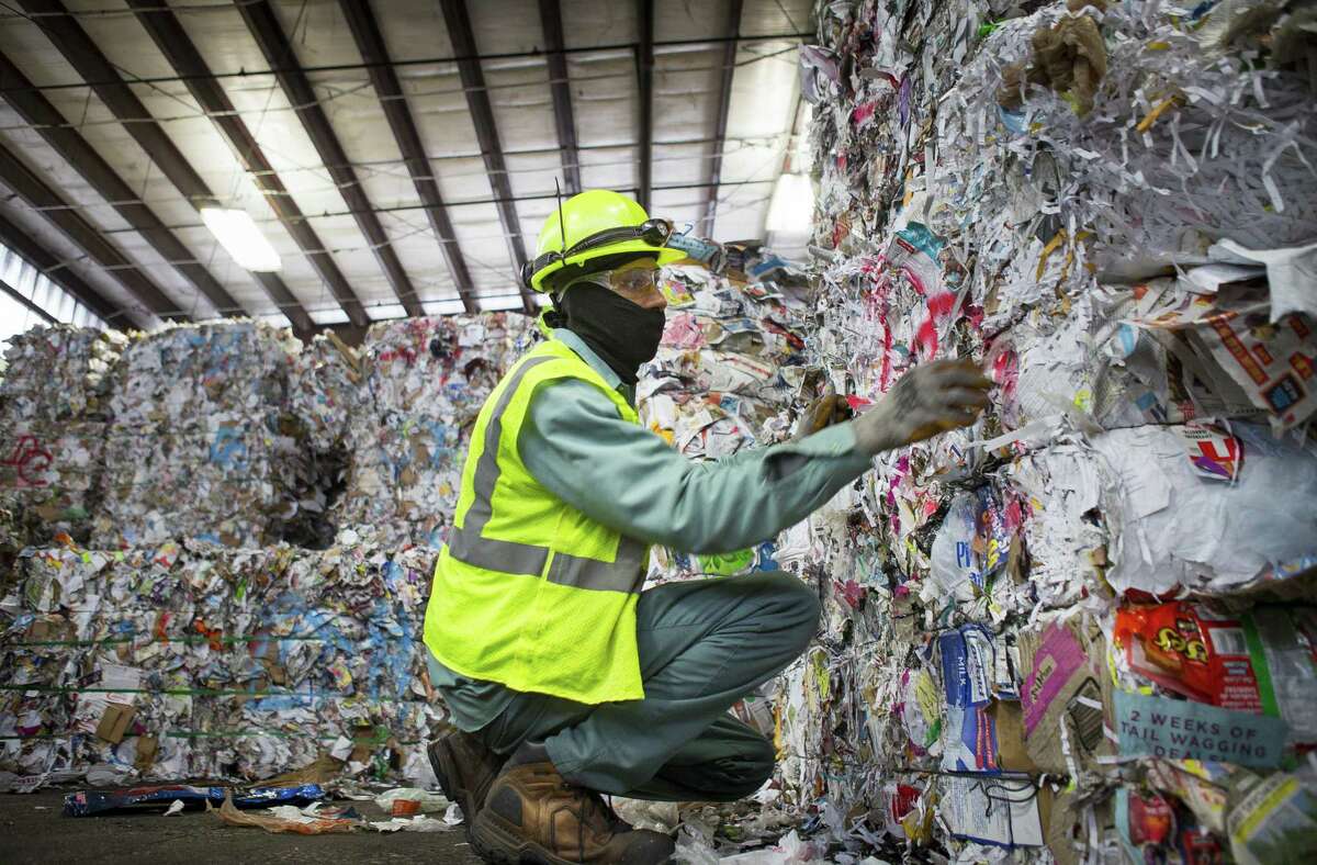 A Waste Management employee removes plastic, which accidentally made it through the sorting process, from a bale of mixed paper that is being prepared to be loaded onto a truck at the company's facility on Gasmer Drive in southwest Houston, Monday, Nov. 19, 2018. NEXT: See photos from an initiative to clean plastics from the Pacific Ocean. 