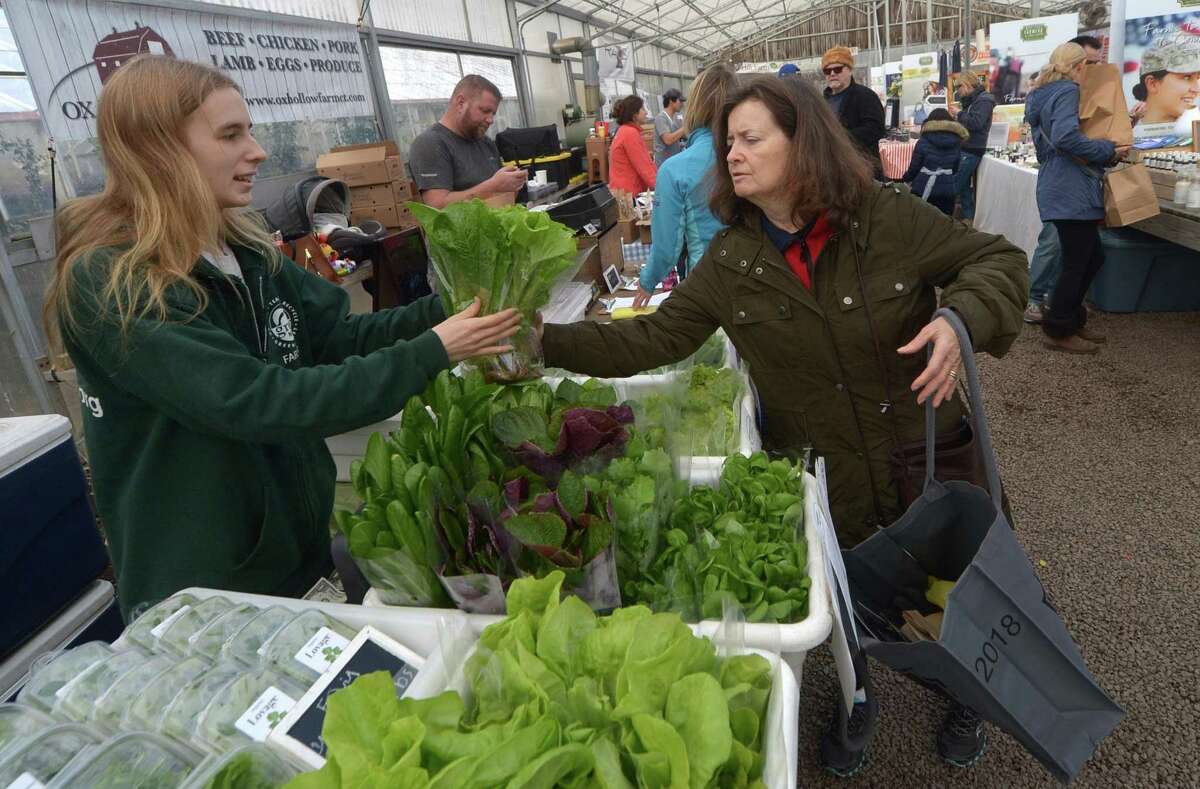 Allie Miller, from Two Guys from Woodbridge, produce sells Patricia Spuani of New Canaan some fresh lettuce during the Westport Winter Farmers Market on Dec. 29 at Gilbertie's Herbs and Garden Center in Westport.