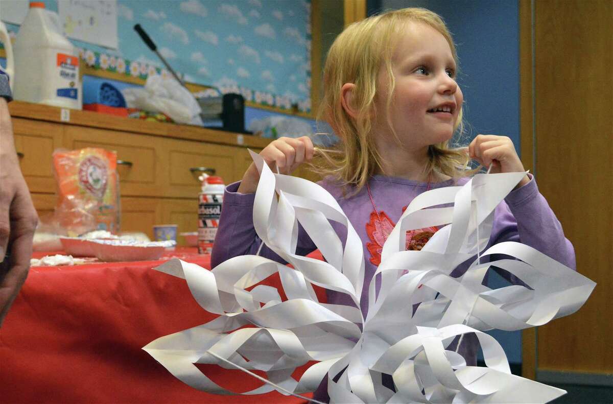 Clara Palmer, 4, of New Canaan, tries on a decoration for size at a science and art snowflake exploration program at the New Canaan Library on Dec. 28, 2018.