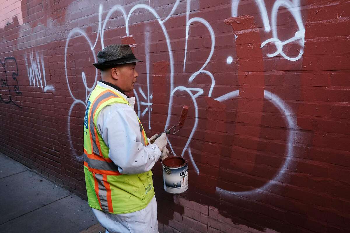 Department of Public Works graffiti unit employee David Yu paints over graffiti in Hang Ah Alley in San Francisco, Calif., on Thursday, December 27, 2018.