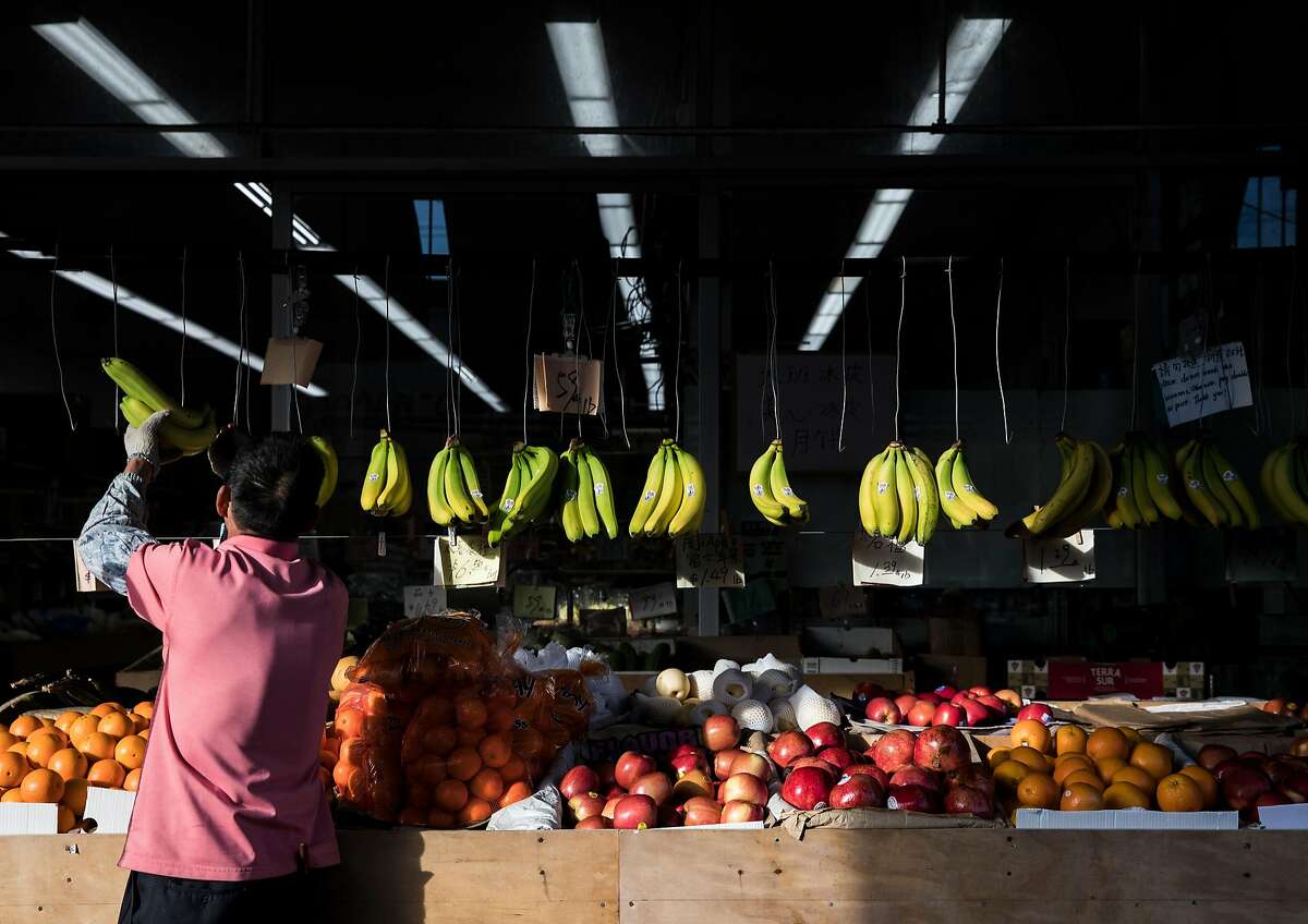 A grocery clerk stocks bananas and other fruits at AAA Vegi Market along Clement Street in the Richmond District of San Francisco, Calif. Wednesday, Dec. 26, 2018.