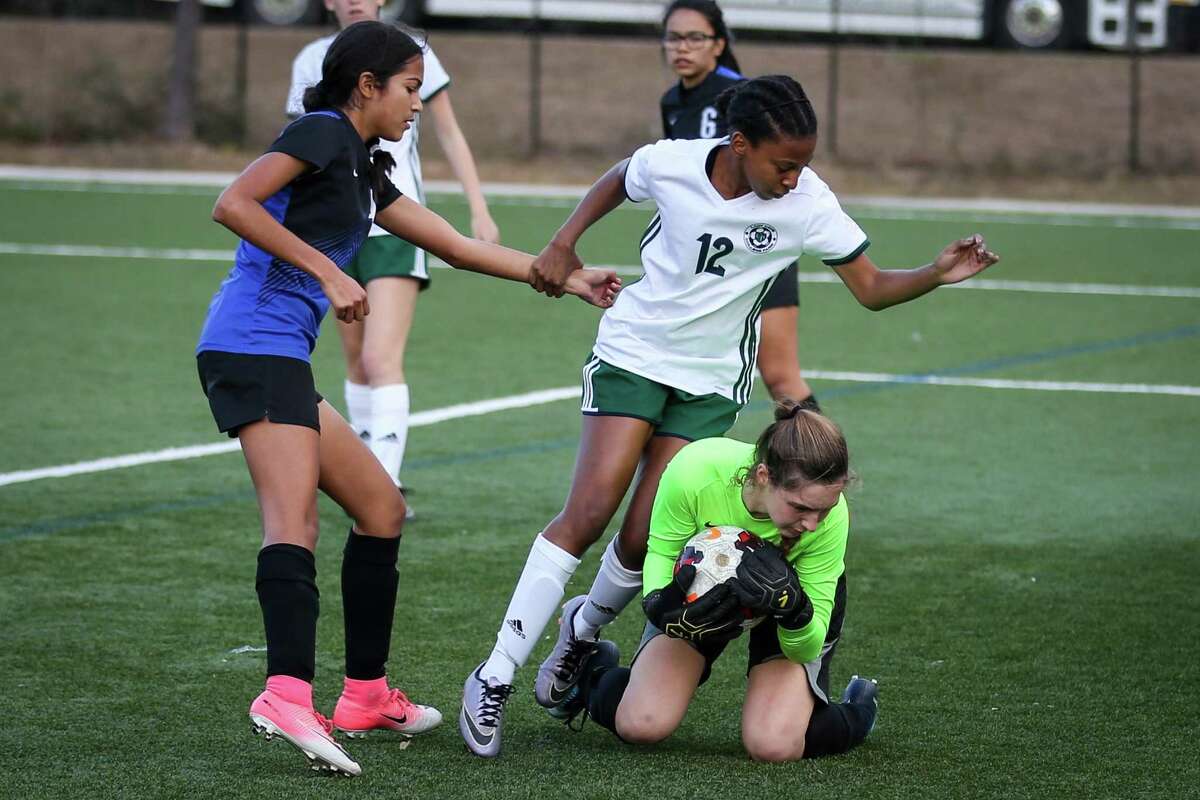 The Woodlands' Kayla Fowler (12) holds onto New Caney's Angela Romero (4) to avoid falling over New Caney's Kali Helms (1) during the girls soccer game on Saturday, Jan. 20, 2018, at the Gosling Sports Complex. (Michael Minasi / Houston Chronicle)