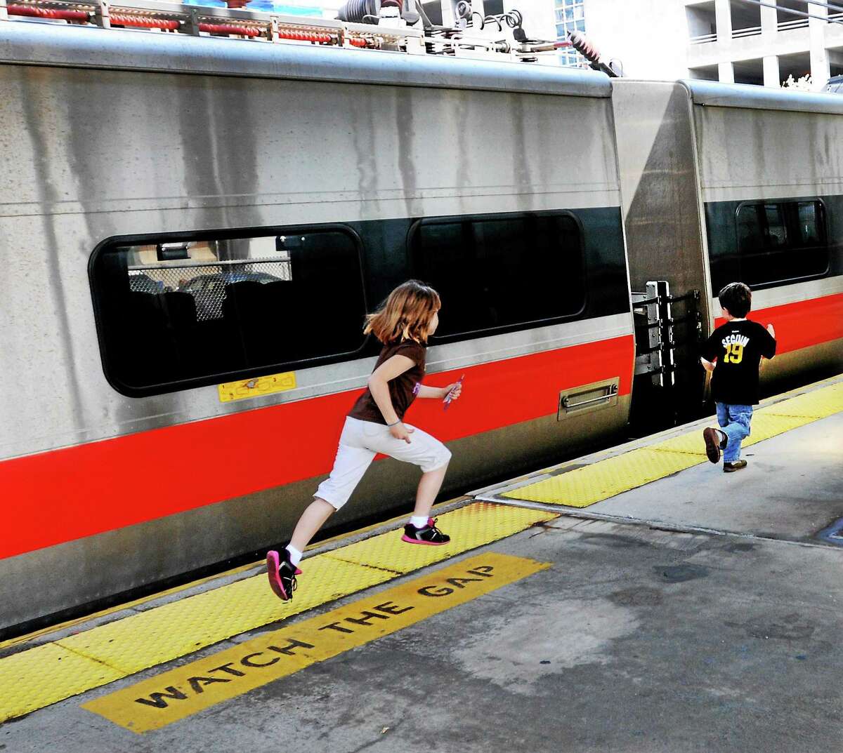 Children run past a static exhibit of a Metro North M8 Electric Multiple Unit train car during a visit to Union Station's celebration of National Train Day in New Haven.