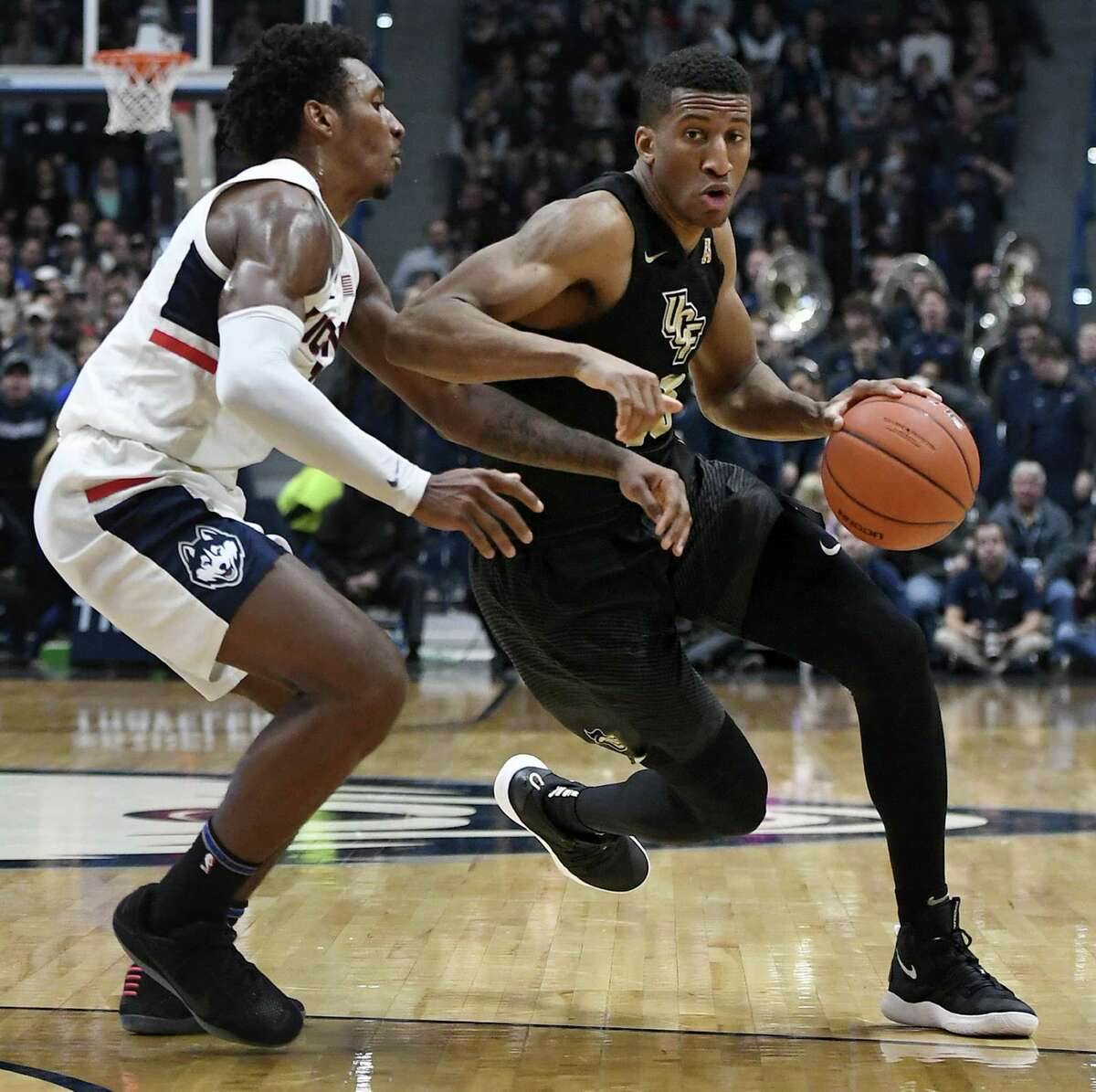 UCF’s Aubrey Dawkins dribbles as UConn’s Christian Vital defends during the first half on Saturday.