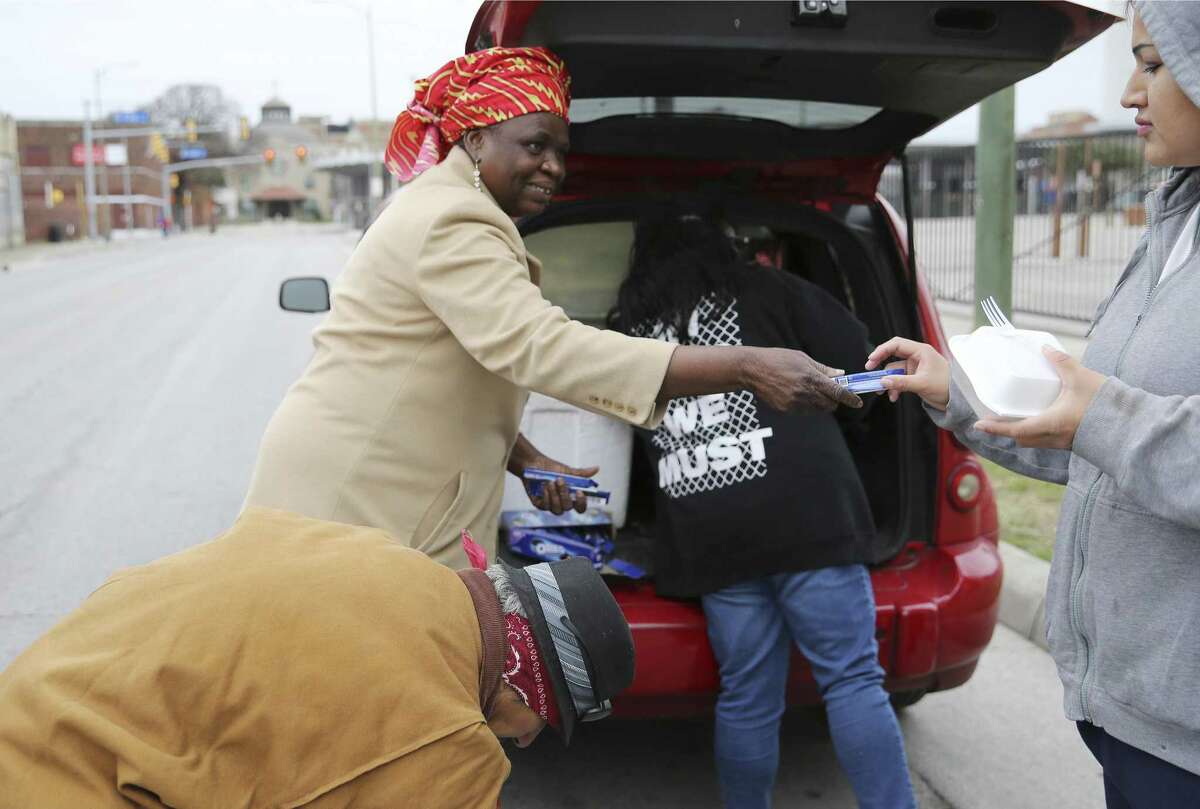 Redeemer?’s Praise Church's Pastor Shetigho Agbuke (left) hands a package of cookies to a meal given to an individual near Houston and Frio Streets on Saturday, Dec. 29, 2018. Church groups and community members pooled their resources to help renovate Redeemer?’s Praise Church, where Agbuke and volunteers feed the homeless and parishioners living in poverty. (Kin Man Hui/San Antonio Express-News)