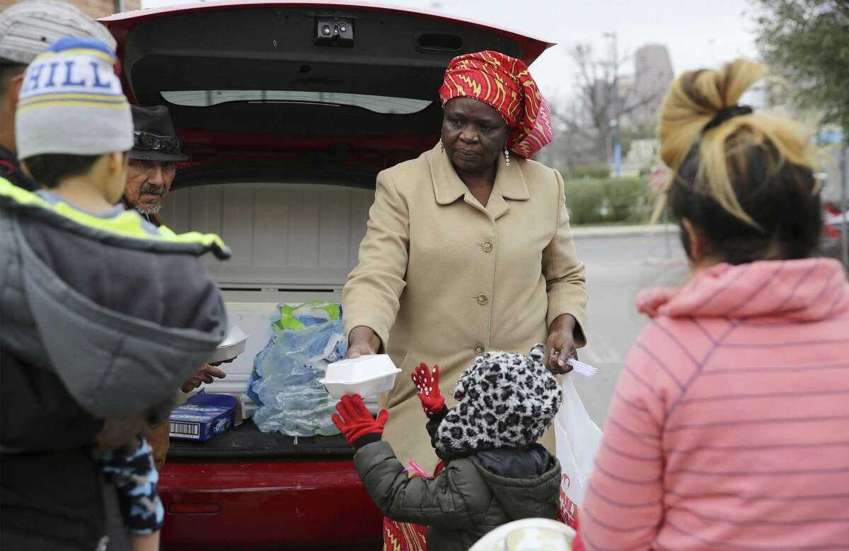 Redeemer?’s Praise Church's Pastor Shetigho Agbuke (center) hands a meal to a child as a family approaches her vehicle near Haven for Hope on Saturday, Dec. 29, 2018. Church groups and community members pooled their resources to help renovate Redeemer?’s Praise Church, where Agbuke and volunteers feed the homeless and parishioners living in poverty. (Kin Man Hui/San Antonio Express-News)