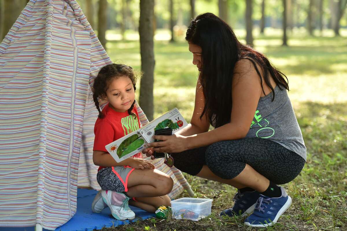 Karmen Askew, 5, reads a book with her mother, Saint Diaz, during Come Play with Pre-K 4 SA last summer at Martin Luther King Park.