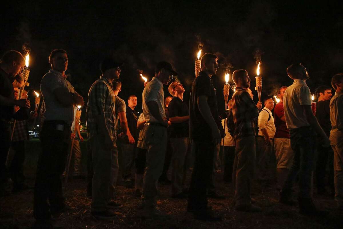 FILE - In this Aug. 11, 2017, file photo, multiple white nationalist groups march with torches through the University of Virginia campus in Charlottesville, Va. Multiple arrests have been made in connection with a white nationalist torch-lit march and rally in Charlottesville, Virginia, last year, federal authorities said Tuesday, Oct. 2, 2018. (Mykal McEldowney/The Indianapolis Star via AP, File)