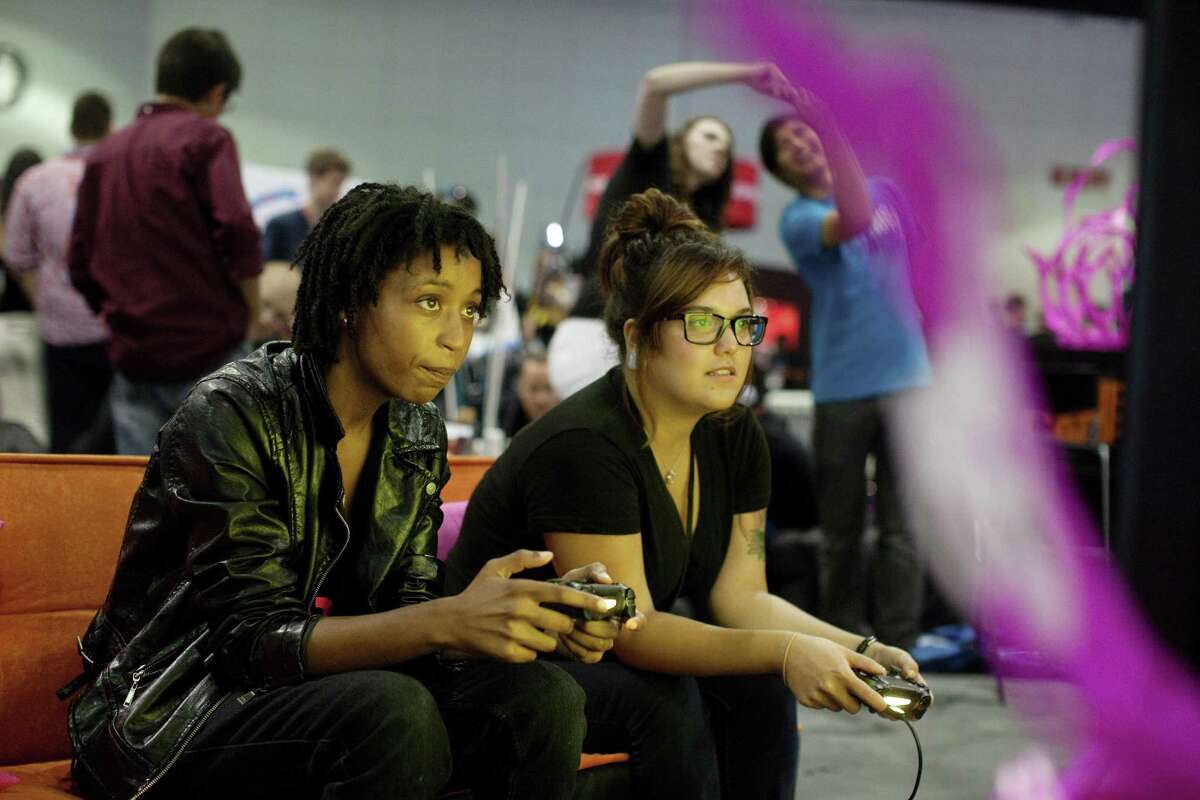 Tion Burton and Elaine Gomez, right, play a video game at the Electronic Entertainment Expo in Los Angeles, June 12, 2014. Where video games once had external enemies, the biggest threat to the culture now seems to come from within, in the form of the harassment of women gamers and creators, and the uproar over "GamerGate." (Emily Berl/The New York Times)
