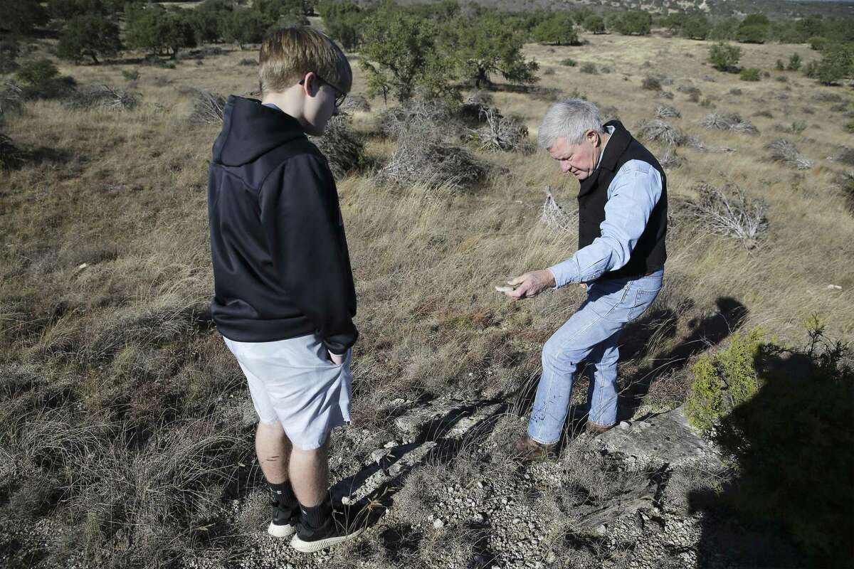 Andy Sansom, manager of the historic Hershey Ranch in Stonewall, shows a found fossil to his grandson, Alex Sansom. Remains of a previous pipeline already litter the land.