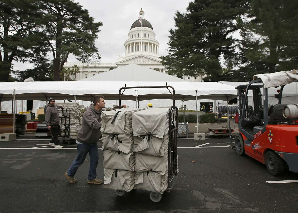 Jacob Blackwell moves a cart load of chairs in preparation for Monday's inauguration of Governor-elect Gavin Newsom, Saturday, Jan. 5, 2019, Sacramento, Calif. Due to the threat of rain, the inaugural ceremonies are expected to be held inside tents erected on the west side of the Capitol. (AP Photo/Rich Pedroncelli)
