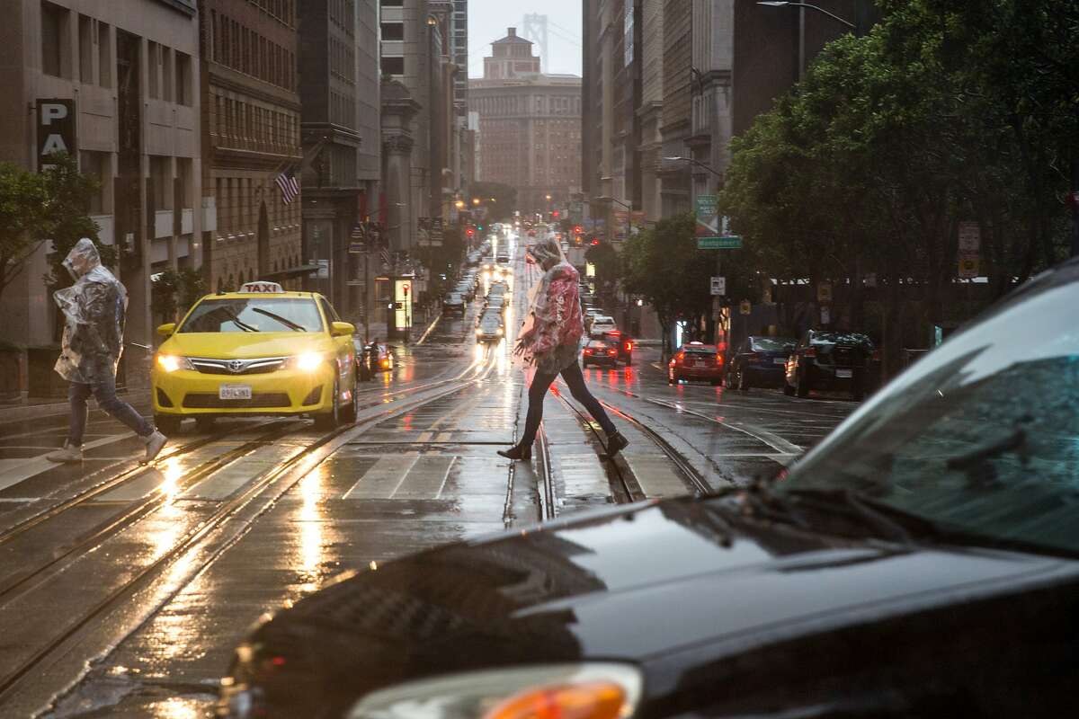 Pedestrians make their way over California Street as rain continued through the weekend in San Francisco on Sunday, January 6, 2019.