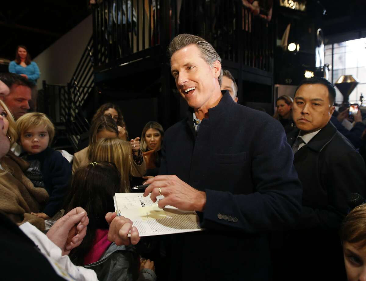 Governor-elect, Lt. Gov. Gavin Newsom, center, autographs a copy of his book, Citizenville for a well-wisher while attending a pre-inaugural Family Event held at the California Railroad Museum, Sunday, Jan. 6, 2019, in Sacramento, Calif. Newsom will be sworn-in as California's 40th governor, Monday. (AP Photo/Rich Pedroncelli)