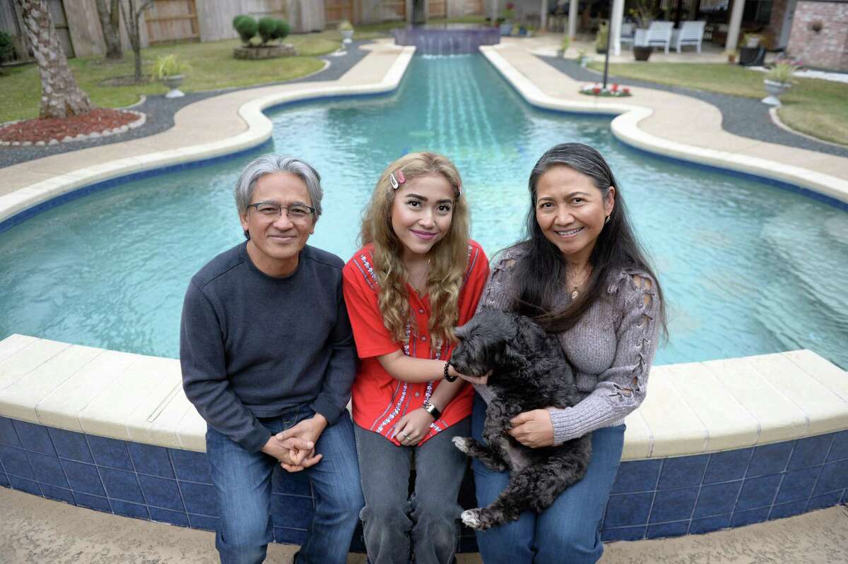 From left, Teguh, Megan and Tanti Inarsoyo sit with dog Miki on the edge of their swimming pool that was inspired by the shape of a Gibson Les Paul guitar on Saturday, Dec. 29, 2018, in Katy.