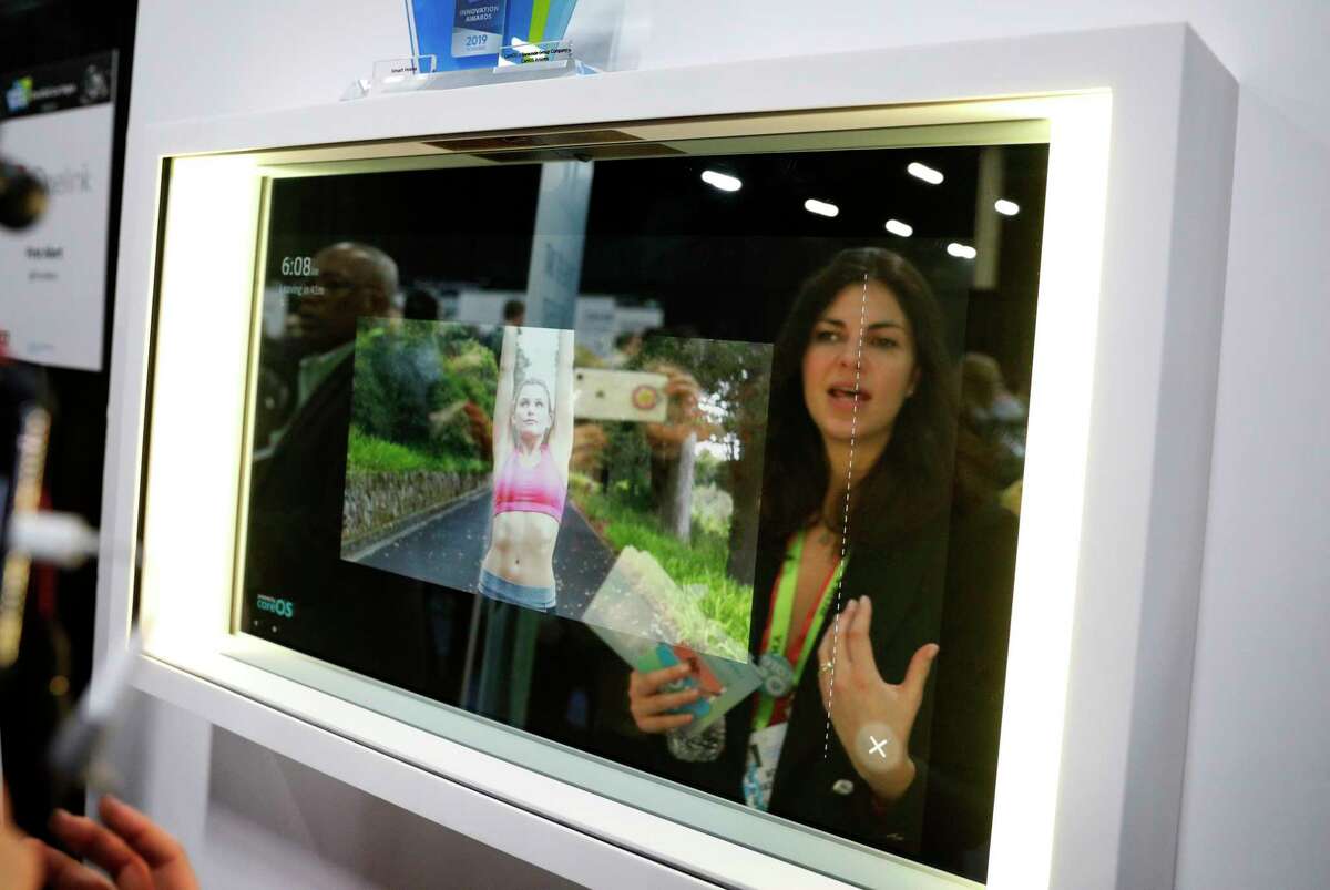 A woman demonstrates the Artemis smart mirror at the CareOS booth during CES Unveiled at CES International, Sunday, Jan. 6, 2019, in Las Vegas. The interactive mirror has video capture, virtual try-ons, facial and object recognition, and can give the user video instruction on specific makeup products, among other things. (AP Photo/John Locher)