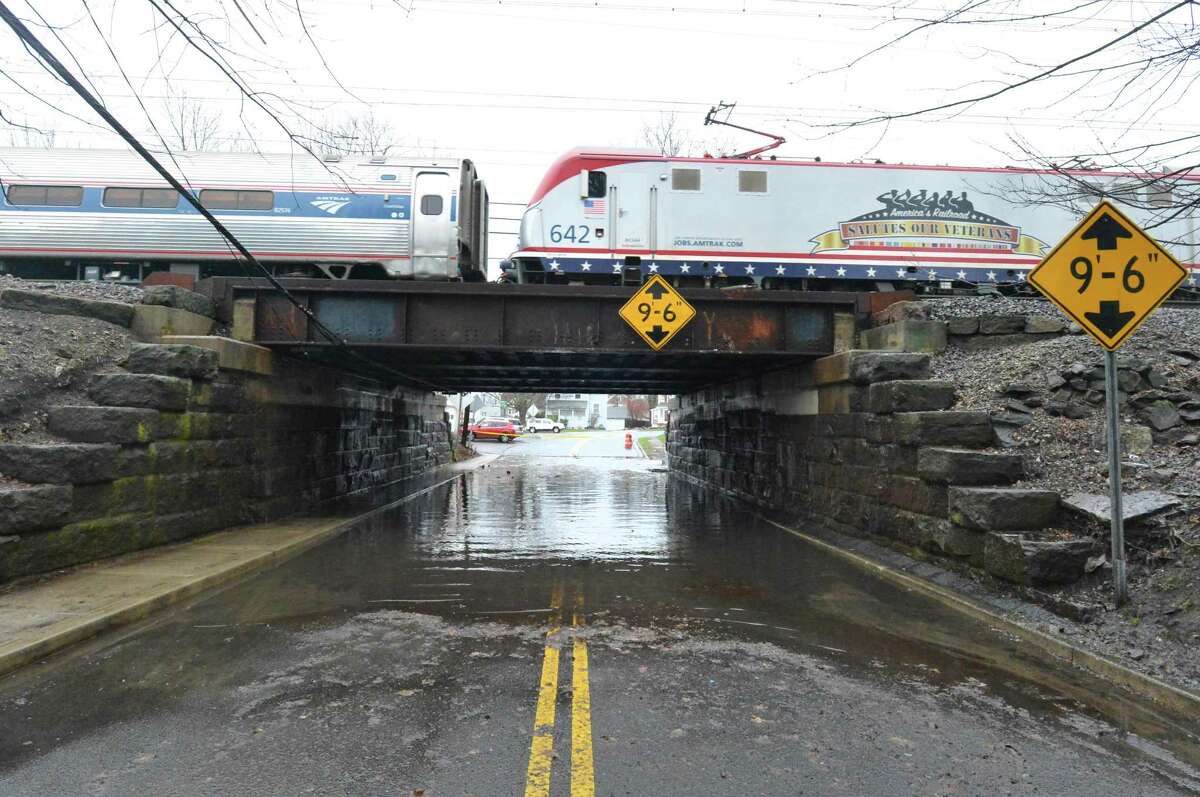 A train crosses the Metro-North Railroad bridge over a flooded Strawberry Hill Avenue in Norwalk.