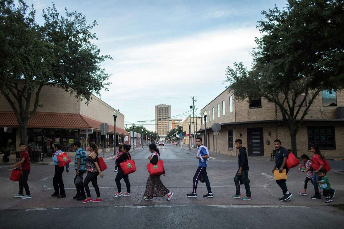 FILE -- Undocumented immigrants walk to a bus station in McAllen, Texas after being processed and released by U.S. Customs and Border Protection on June 24, 2018. Though construction of an actual wall has not begun, and funding for it has yet to be provided by Congress, the symbolism and reality of what it means has grown. (Tamir Kalifa/The New York Times)