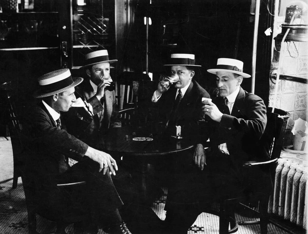 Four men in straw boater hats enjoy a last drink together before Prohibition begins in 1919.