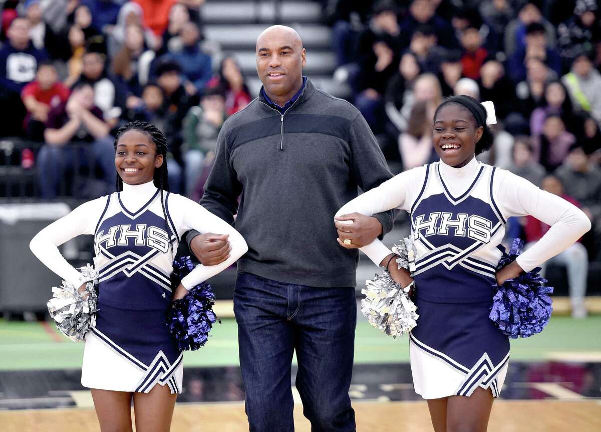 Southern Connecticut State University men's basketball head coach and former professional basketball and baseball player Scott Burrell (center) is escorted to center stage by Hillhouse High School cheerleaders Angelie Alcin (left) and Kuniya Asobayire (right) during the Walter Camp Staying in School Rally at the Floyd Little Athletic Center in New Haven on January 10, 2019.