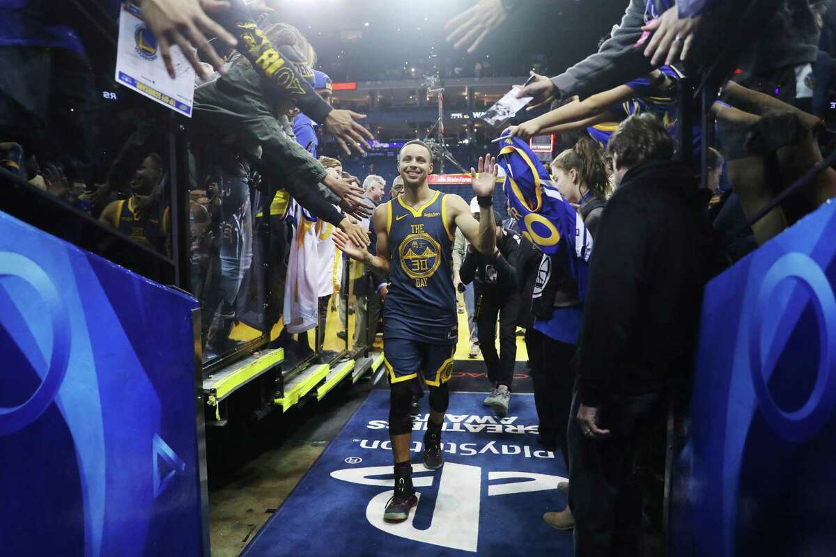 A fan grabs Golden State Warriors' Stephen Curry leaves the floor following the Warriors' 110-93 win over Memphis Grizzlies during NBA game at Oracle Arena in Oakland, Calif. on Monday, December 17, 2018.