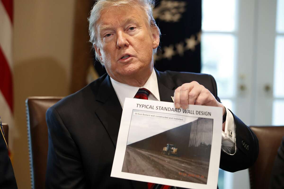 President Donald Trump holds a photo as he leads a roundtable discussion on border security with local leaders, Friday Jan. 11, 2019, in the Cabinet Room of the White House in Washington.