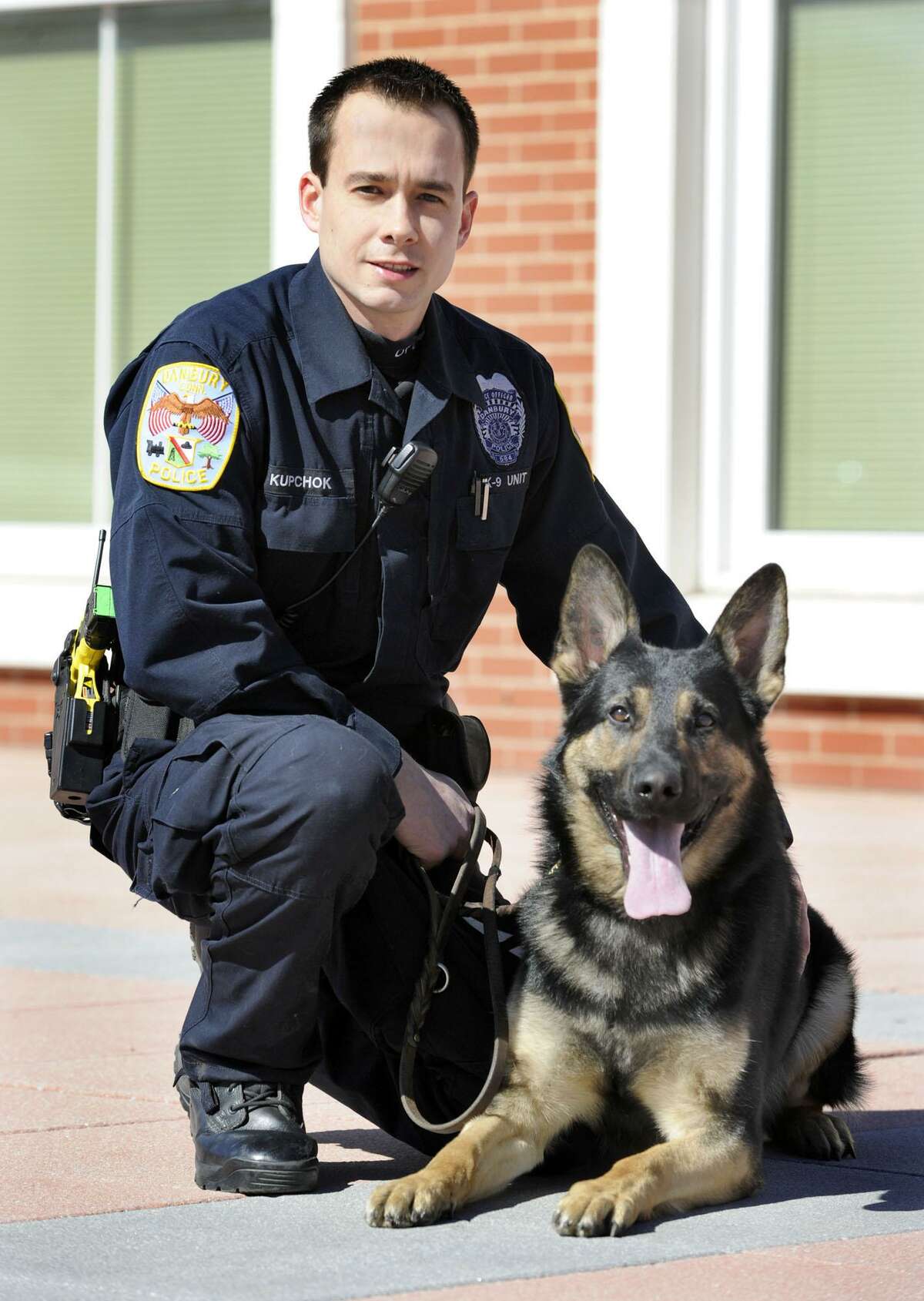 File photo of Danbury Police Officer Travis Kupchok crouches with Koda, his canine partner, Tuesday, March 6, 2012.