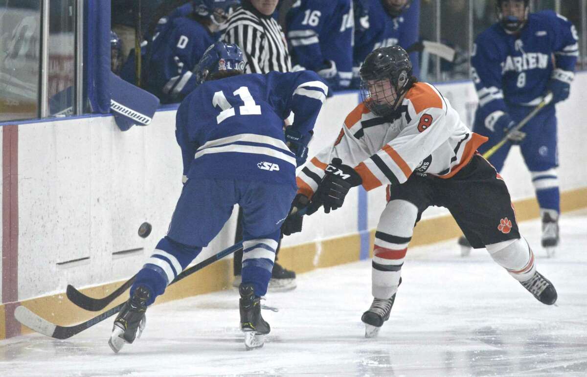 Ridgefield’s Kees van Wees (8) and Darien’s Brian Zaffino (11) fight for the puck in the boys ice hockey game between Darien and Ridgefield high schools on Friday night at Winter Garden Ice Arena in Ridgefield.