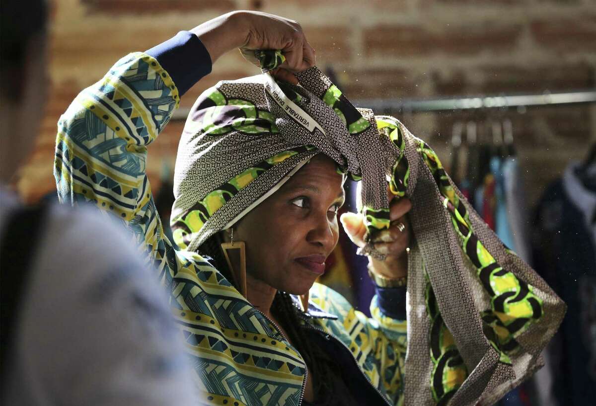 Unyime Udosen shows how to wrap and wear a head tie at her vendor's booth at the Olaju African Market Creative Arts Festival which showcases arts from the African continent at the Blue Star Arts Complex on Saturday, Jan. 12, 2019. As one of the officially recognized events of DreamWeek which promotes the teachings of Dr. Martin Luther King, the Olaju Festival provides enlightenment of African art and culture to San Antonio. (Kin Man Hui/San Antonio Express-News)