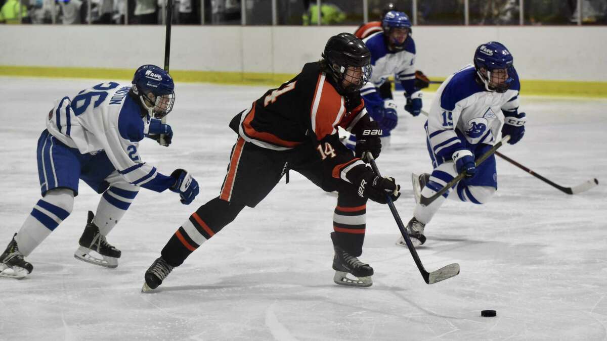 Ridgefield’s Will Forrest (14) gets in front of Darien’s Luke Johnston (26) and John Reid (19) during a boys hockey game at the Darien Ice House on Saturday.