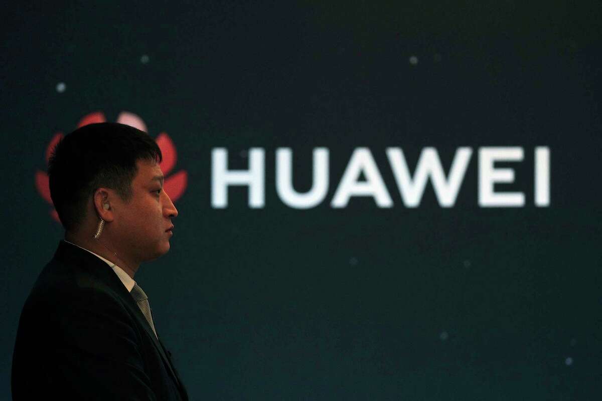 In this Jan. 9, 2019, photo, a security guard stands near the Huawei company logo during a new product launching event in Beijing. The Chinese Foreign Ministry said late Friday, Jan. 11, 2019, it is "closely following the detention of Huawei employee Wang Weijing" on charges of allegedly spying for China, and has asked Poland to "handle the case lawfully, fairly, properly and to effectively guarantee the legitimate rights of the person, his safety and his humanitarian treatment," according to state broadcaster CCTV. (AP Photo/Andy Wong)