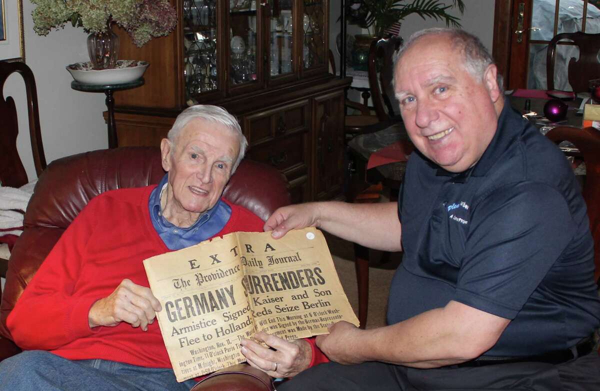 Dick Wood, left, a retired WTEN-TV News anchor and Army veteran, presents a 100-year-old copy of The Providence Daily Journal to Gene Loparco in Wood?s Latham home. The newspaper leads with stories marking the end of World War I. (Linda Loparco)