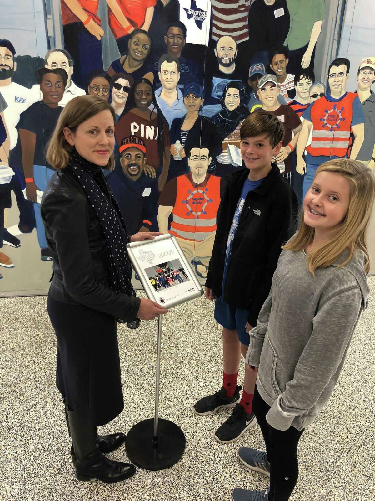 Memorial Middle School eighth graders Jack Bartlett and Ashley Mahood chat with artist Sarah Fisher in front of her larger than life painting, “That was Harvey. This is Houston,” while it was on display at the Spring Branch ISD school.