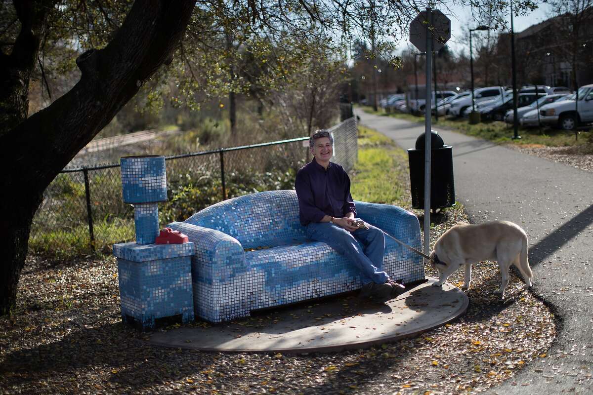Chris Kump tries out a couch made of tile at a living room set near W. Grant St. with his dog Hank on Saturday, Jan. 12, 2019, in Healdsburg, Calif.