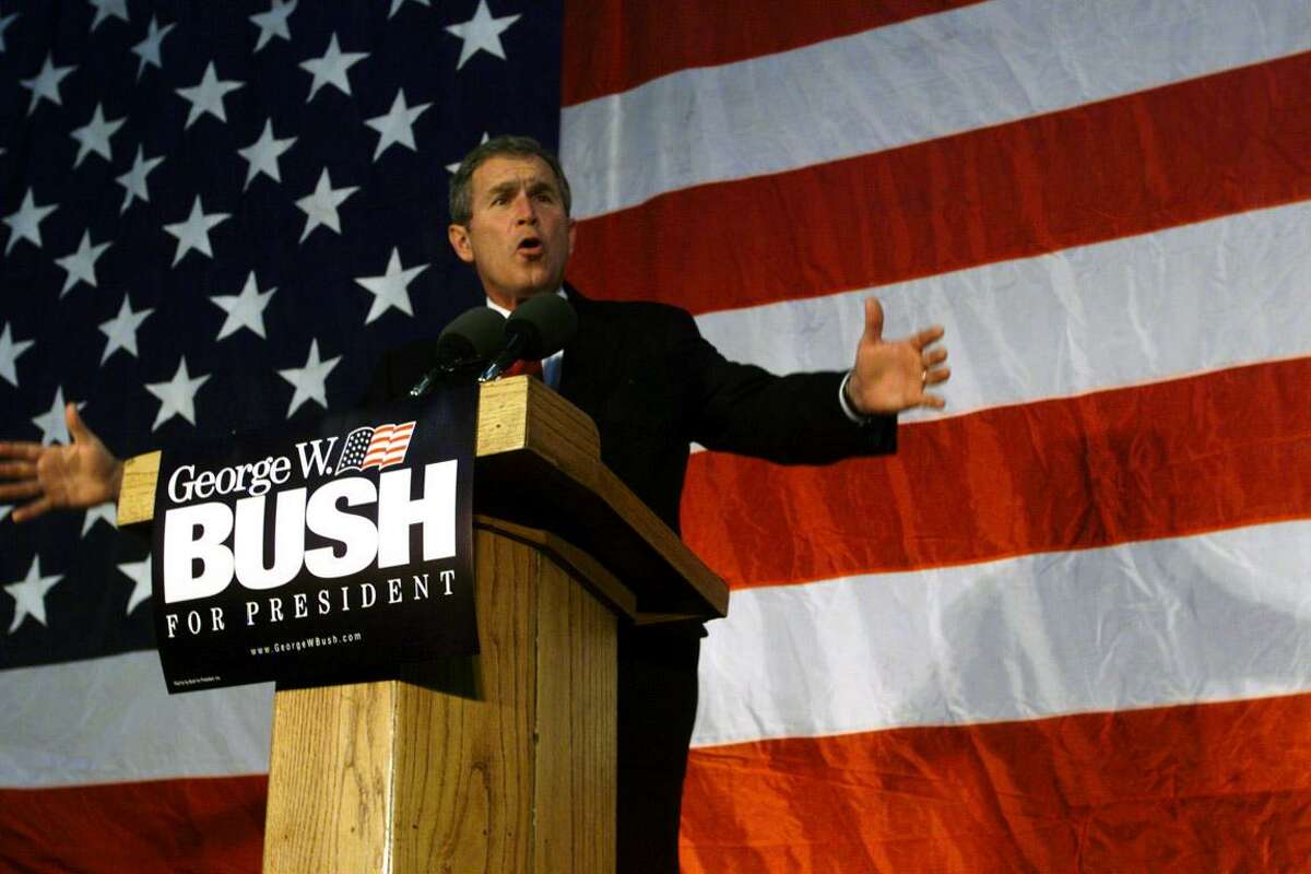 Then Texas Governor George W. Bush gestures to his supporters at a rally in Cedar Rapids, Iowa during the 2000 presidential campaign.